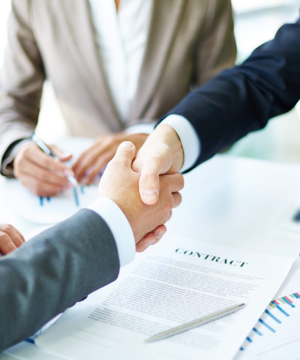 Making agreement Image of business partners handshaking over business objects on workplace