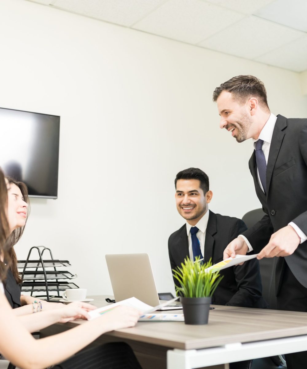 Colleagues Discussing In A Meeting Male accountant showing financial document to female clients in office